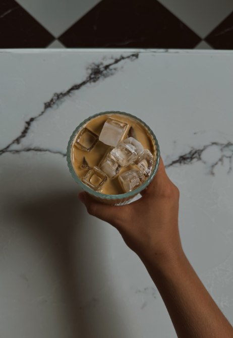 An iced latte held over a marble counter